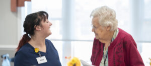 caregiver and an elderly woman smiling together