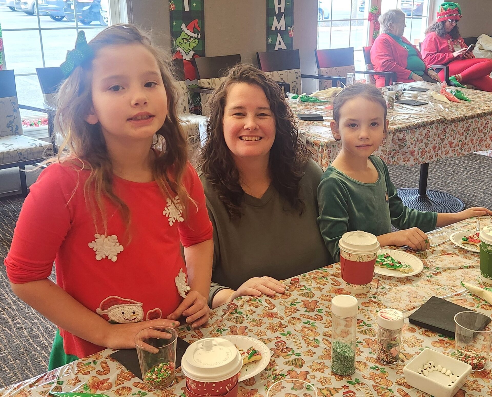 two young girl and a woman smiling and decorating cookies