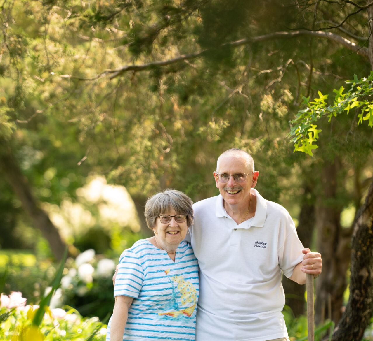 Happy 55+ couple walking among greenery on sunny day