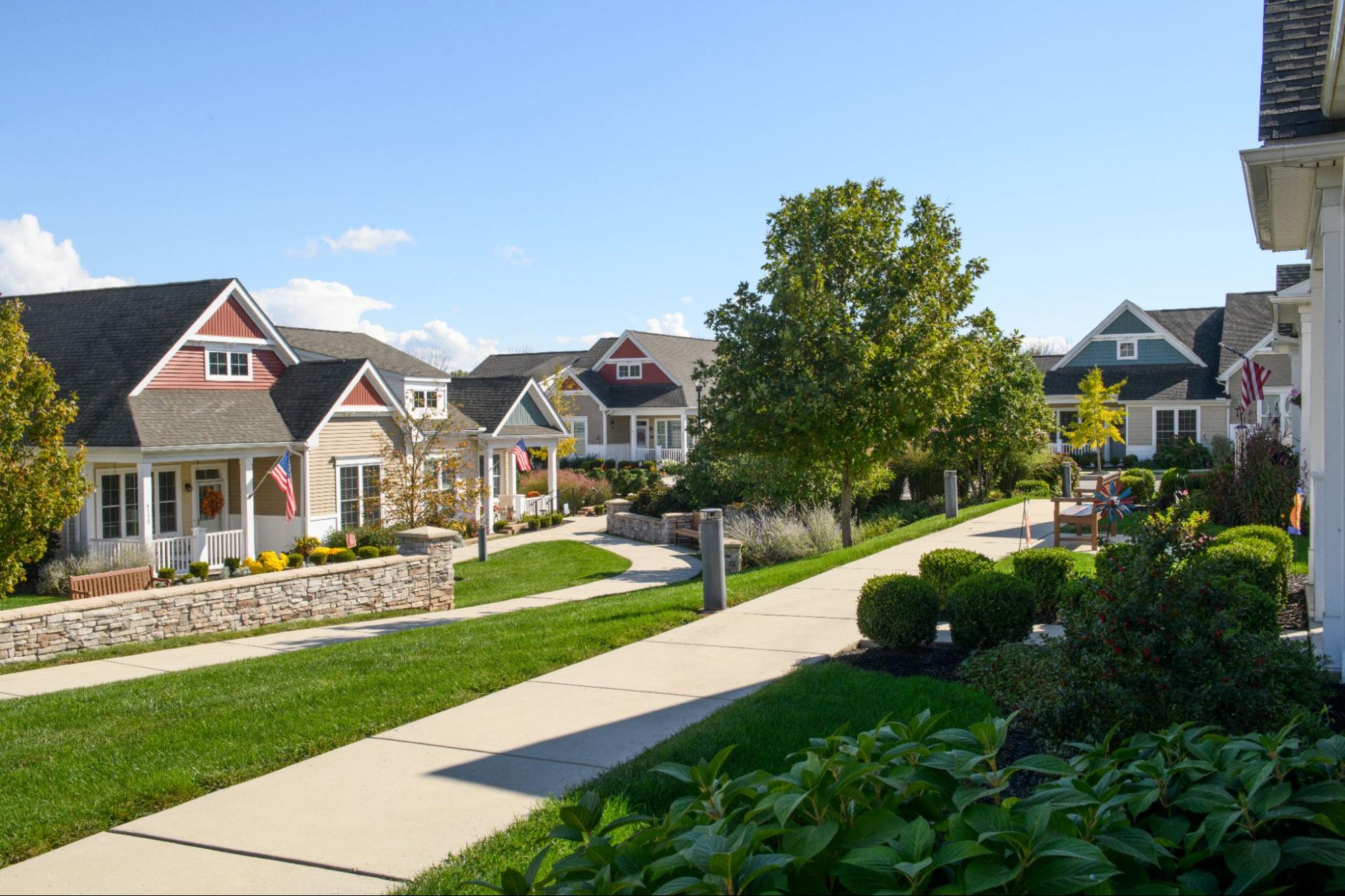 A cluster of beautiful cottage-style homes bordering a paved pathway, illustrating the inviting design of pocket neighborhoods.