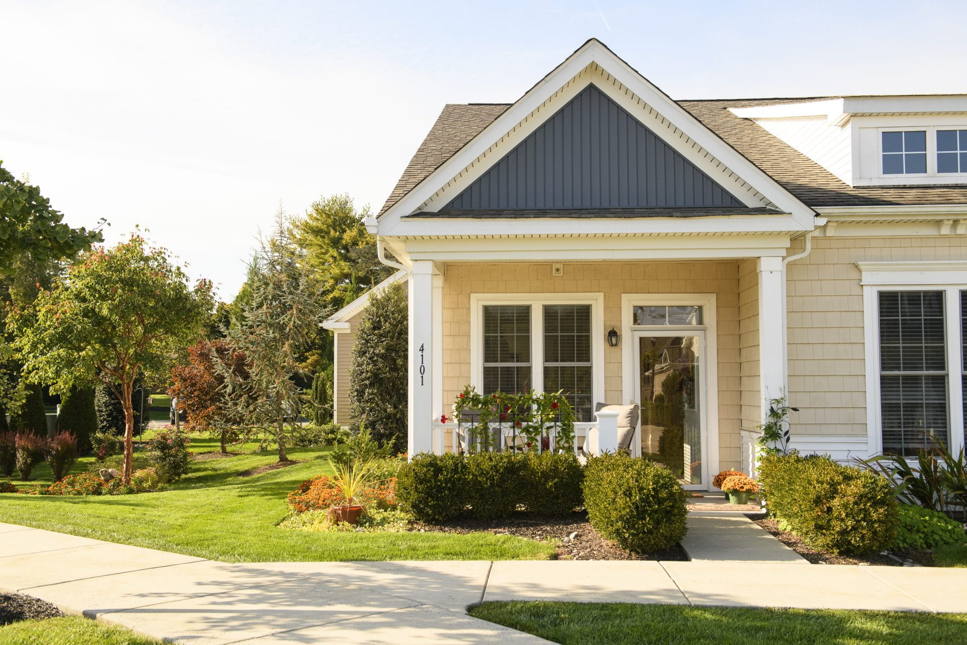 A bright, welcoming cottage with a small front porch and vibrant landscaping, showcasing the ideal home design found in pocket neighborhoods for seniors.